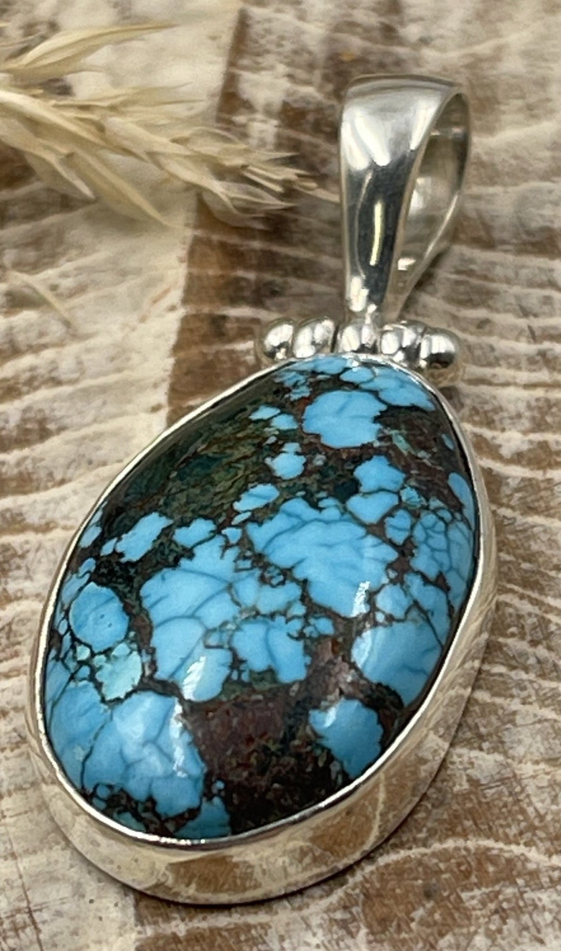 Turquoise pendant with silver setting on a wooden surface