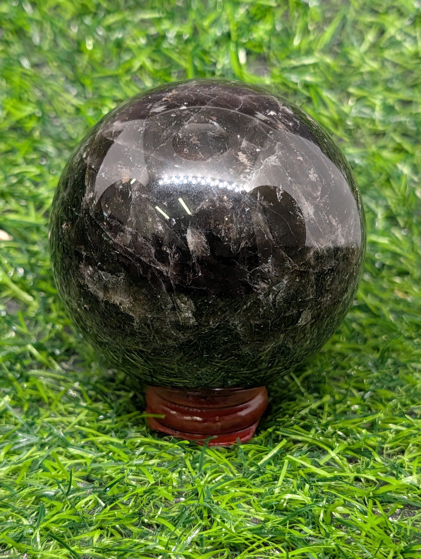 Black marble sphere on a grassy surface
