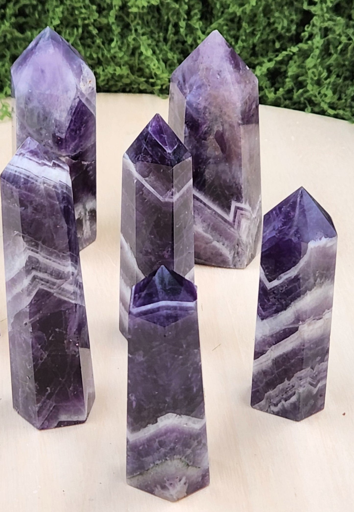 Set of purple crystal points on a white surface with greenery in the background