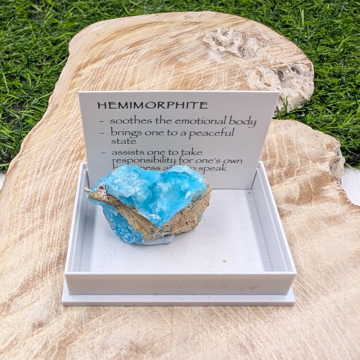 Blue crystal on a white stand with descriptive card on a natural stone background