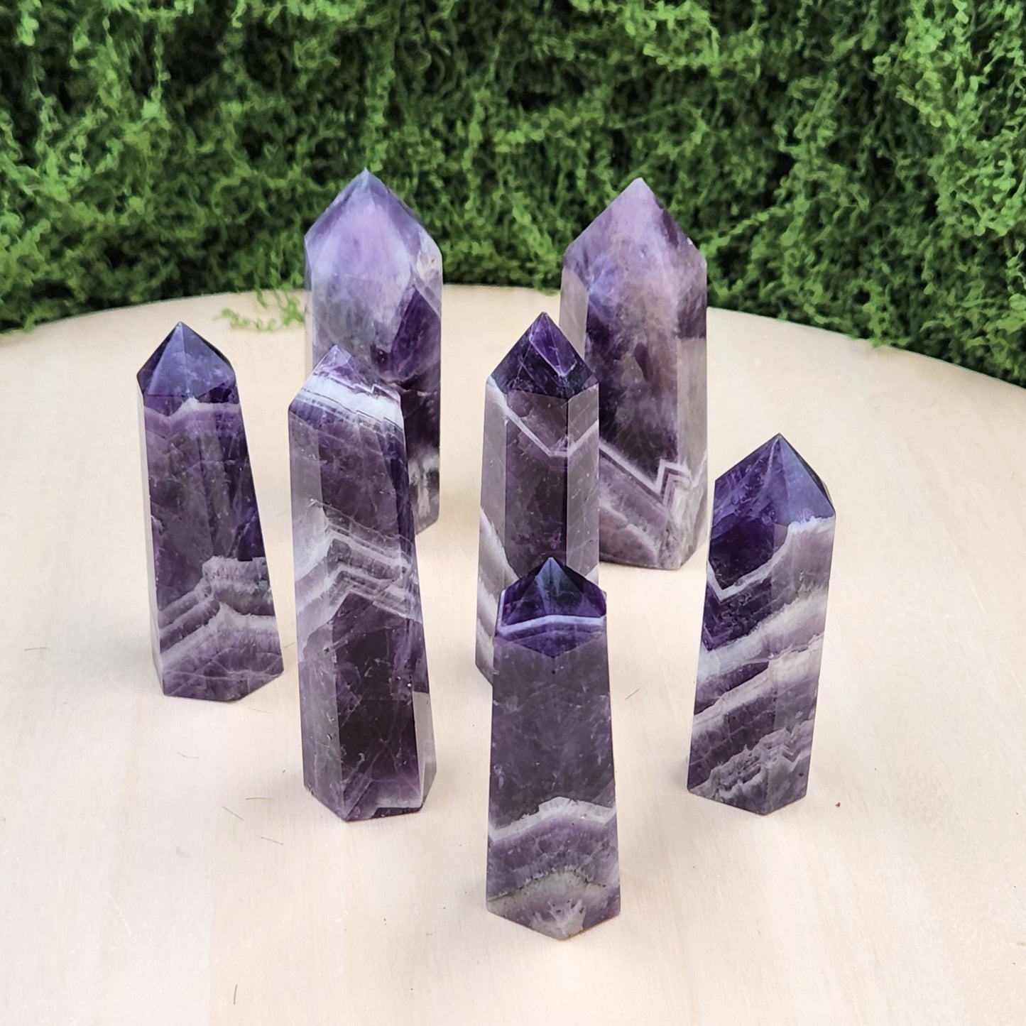 Set of purple crystal points on a white surface with greenery in the background