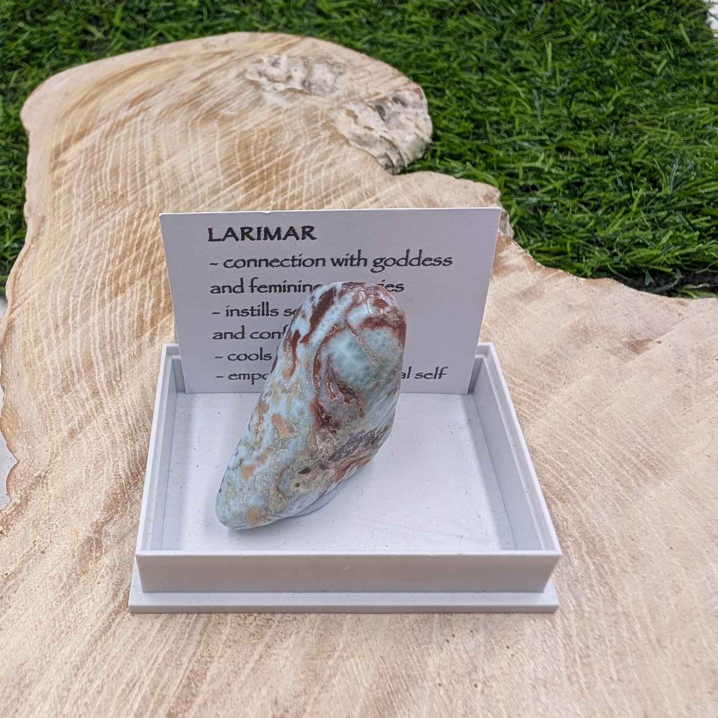 Larimar stone in a display box with an informational card on a natural background