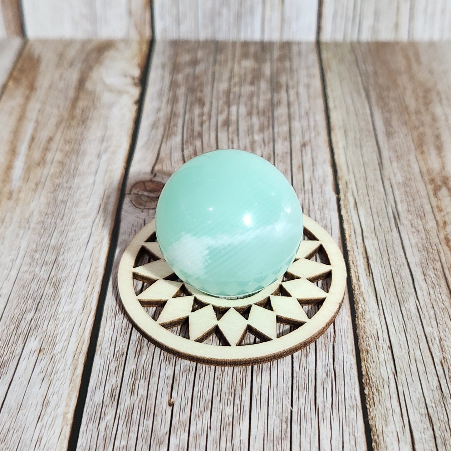 Decorative door handle with a turquoise ball and geometric design on a wooden surface