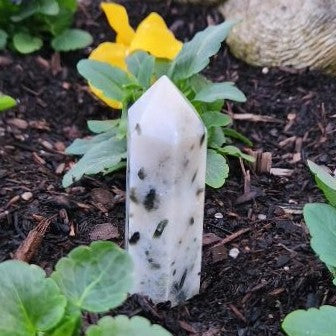 Crystal or stone with greenery and a yellow flower in the background