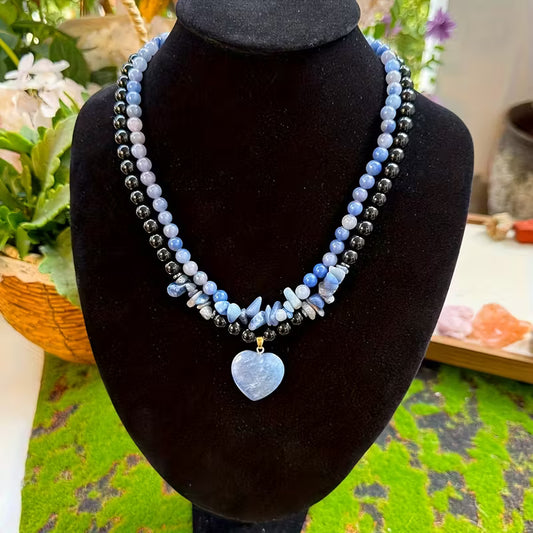 Necklace with blue and black beads on a black mannequin bust.
