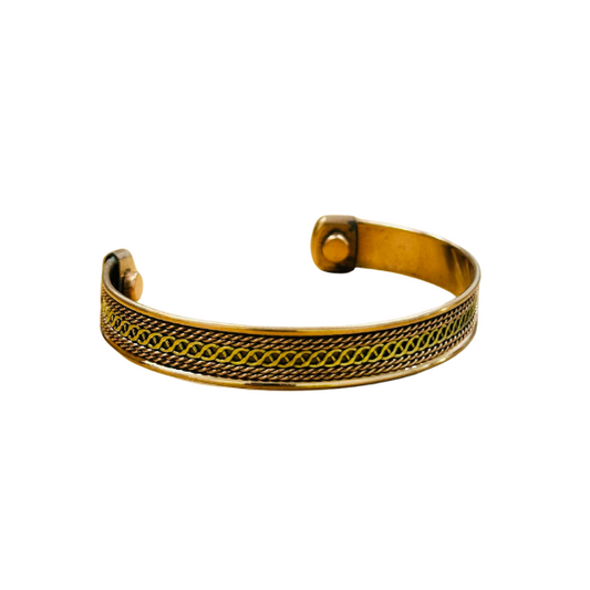 A gold-colored metal bracelet with a patterned design.