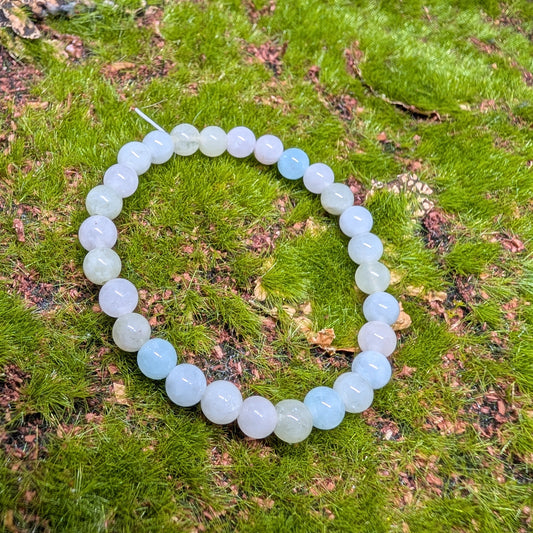 White beaded bracelet on a green mossy surface