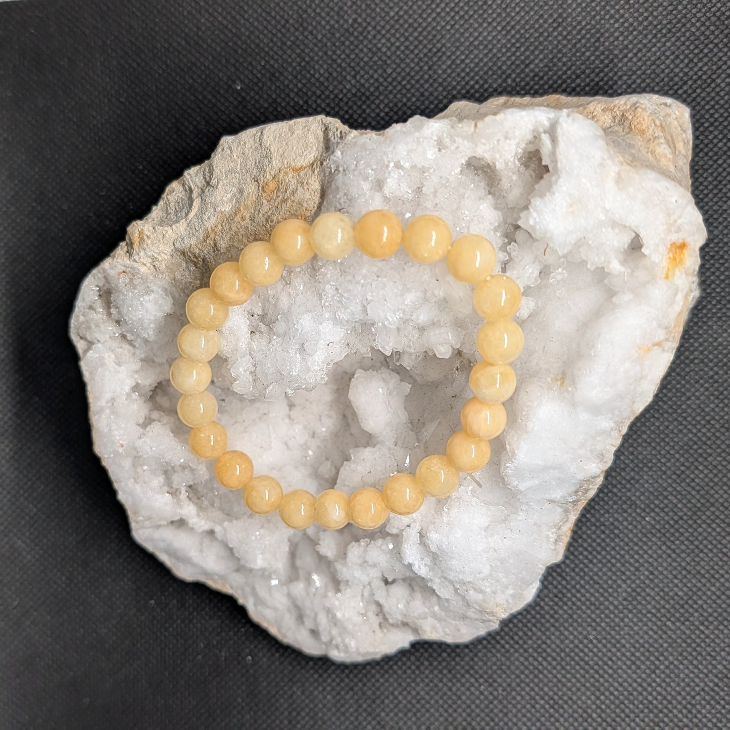 Yellow beaded bracelet on a white crystal formation against a black background