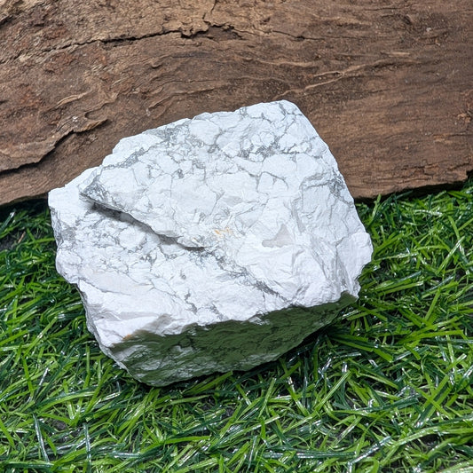 White textured stone on artificial grass with wooden background