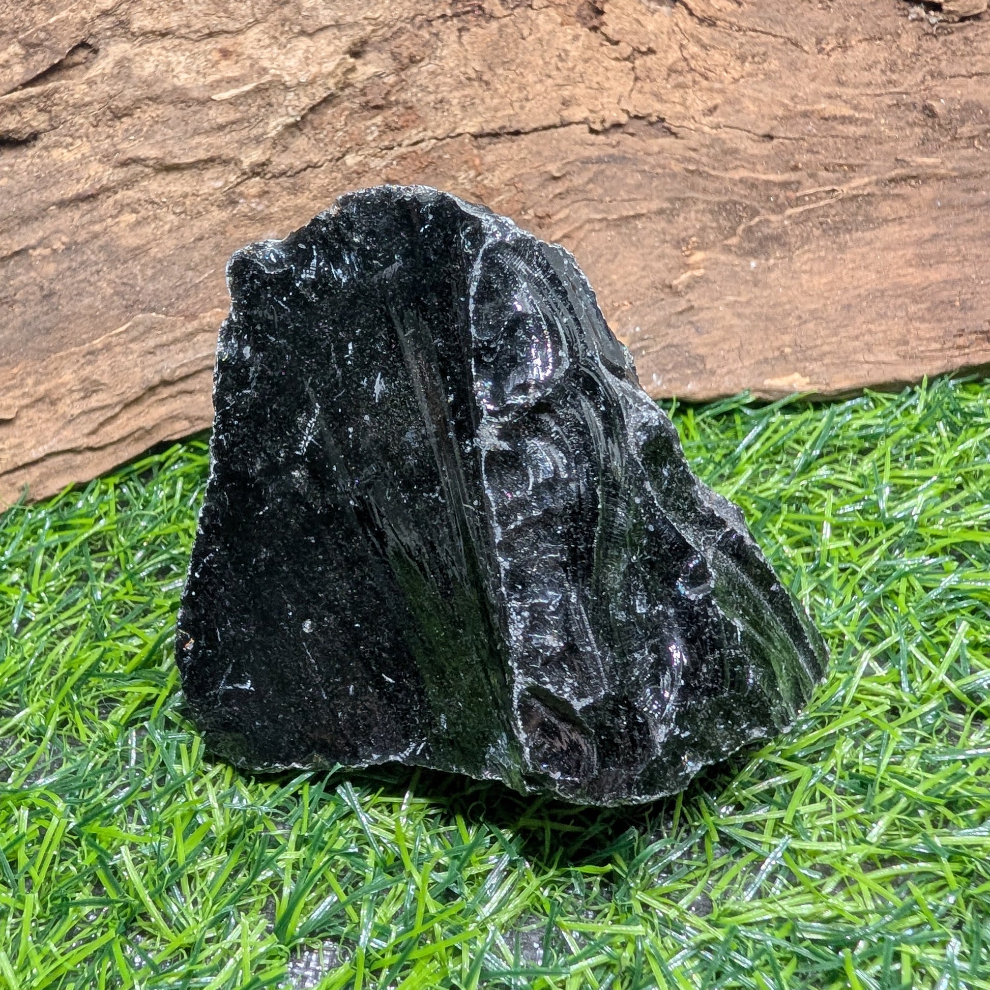 Black crystal on grass with wooden background