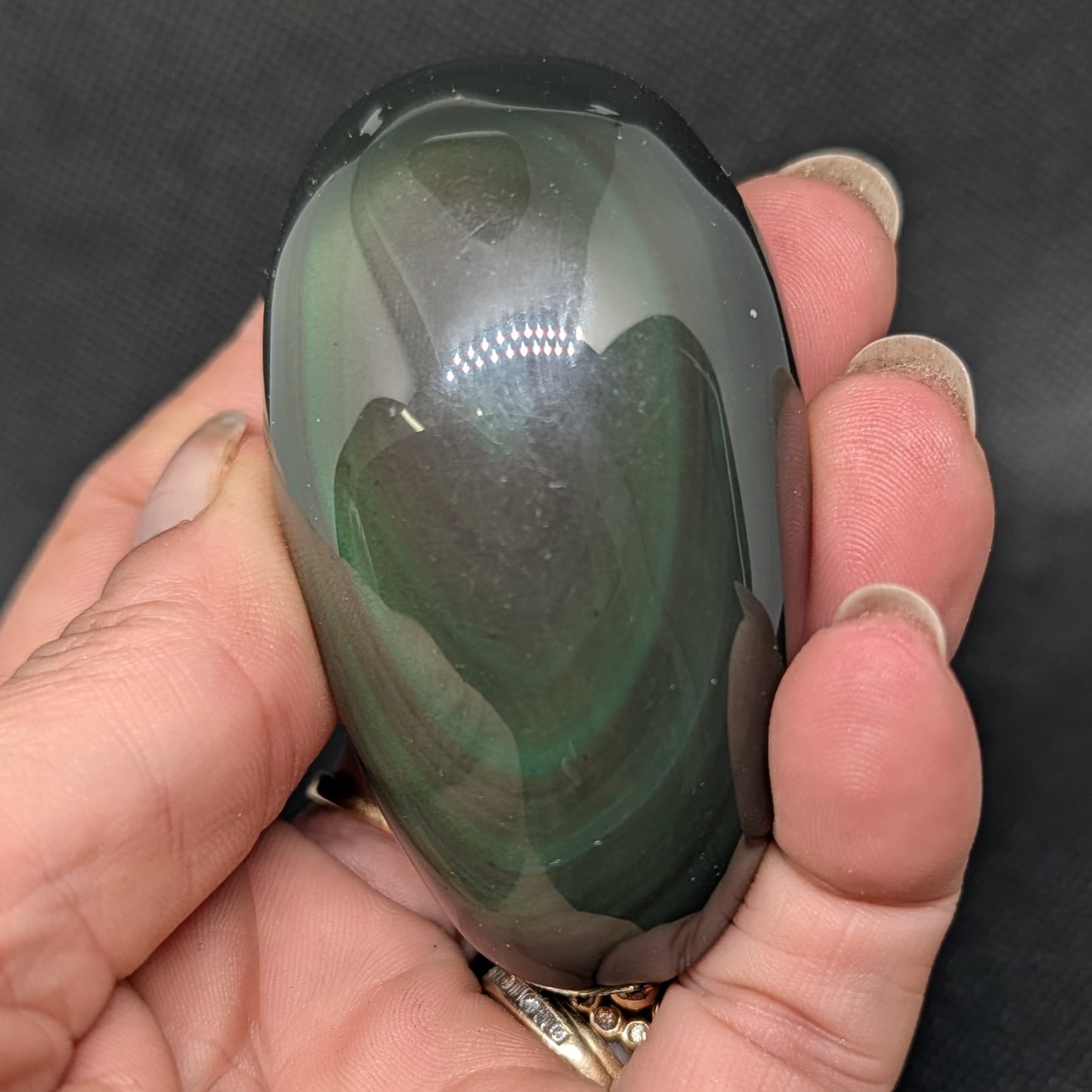 Hand holding a green stone with a dark background