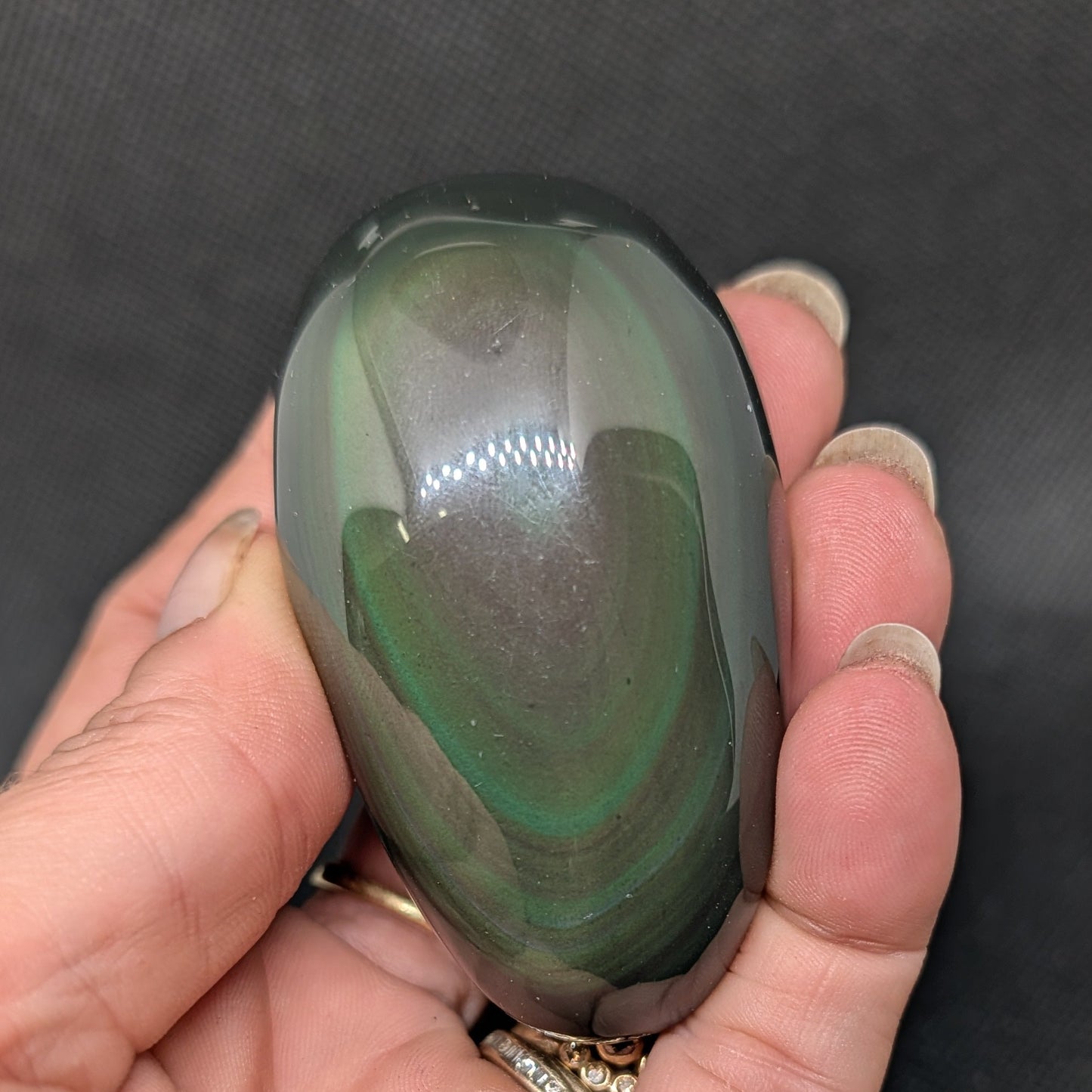 Hand holding a green and brown stone against a dark background