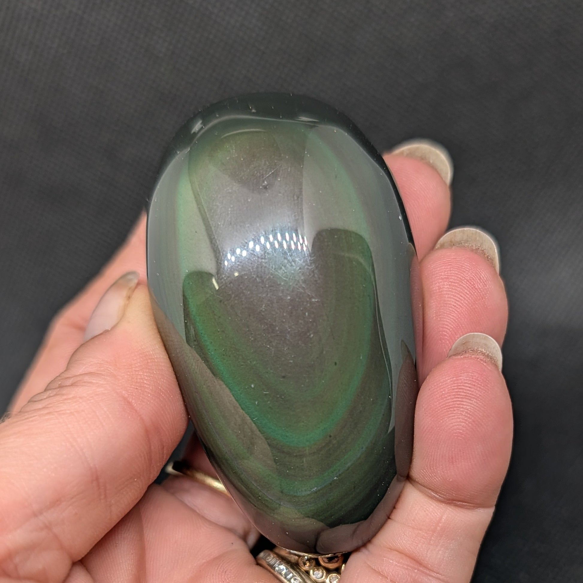 Hand holding a green and brown stone against a dark background
