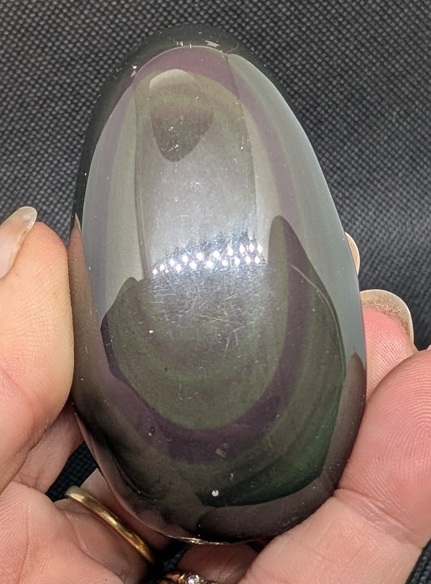 Hand holding a large, smooth stone with a dark exterior and light interior against a dark background