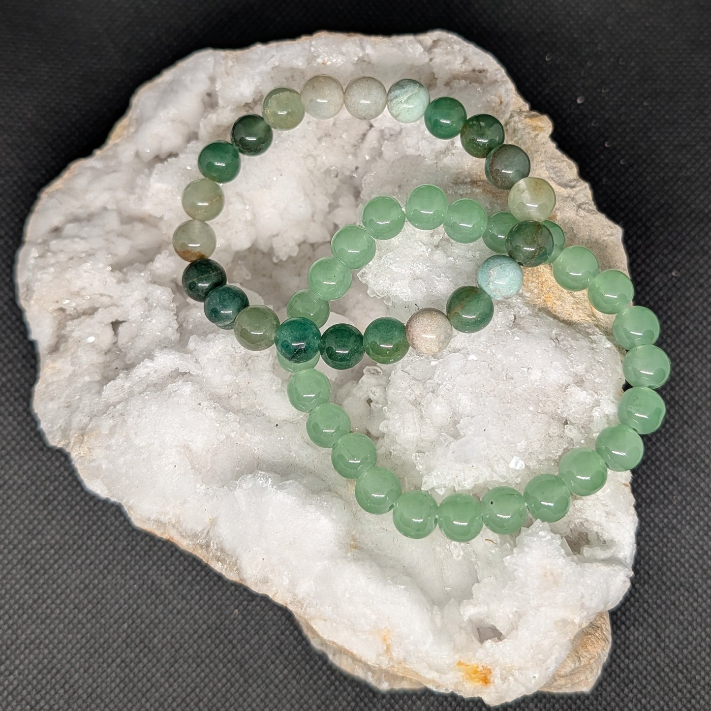 Green beaded bracelet on a white stone surface with a dark background