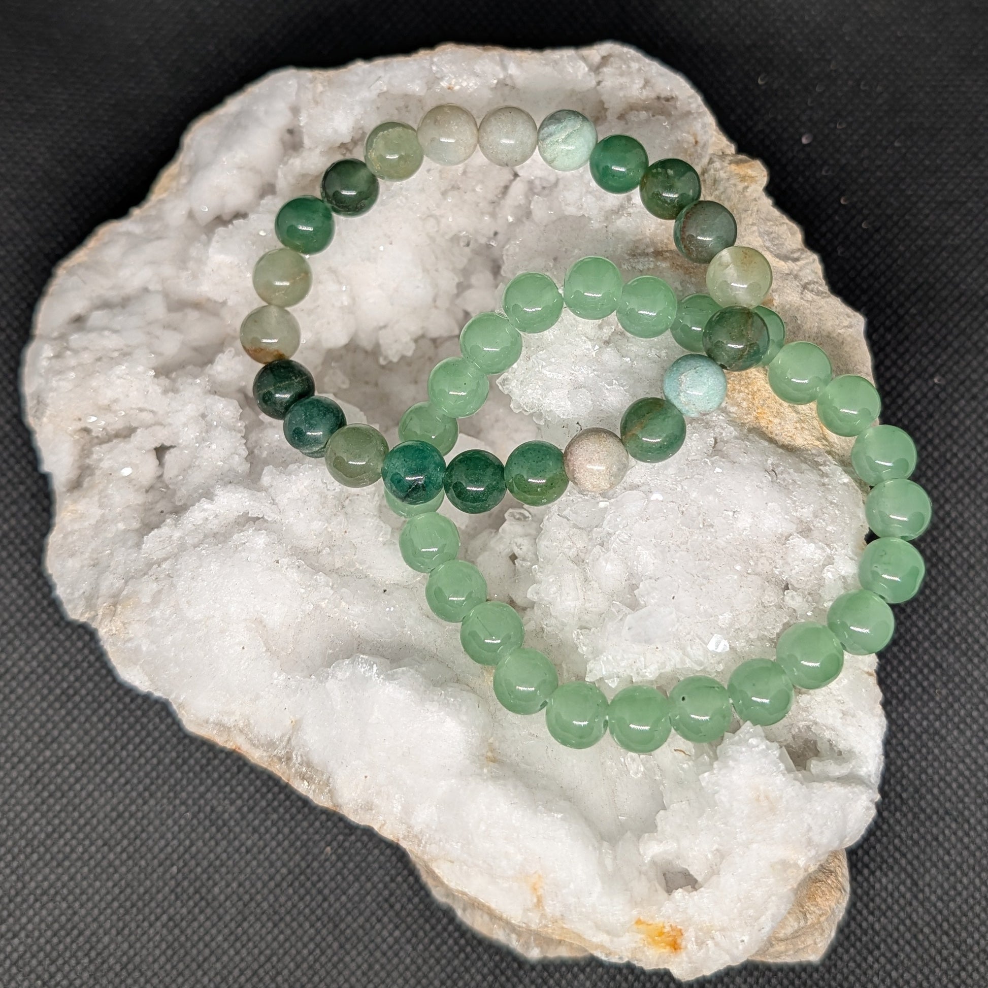 Green beaded bracelet on a white stone surface with a dark background