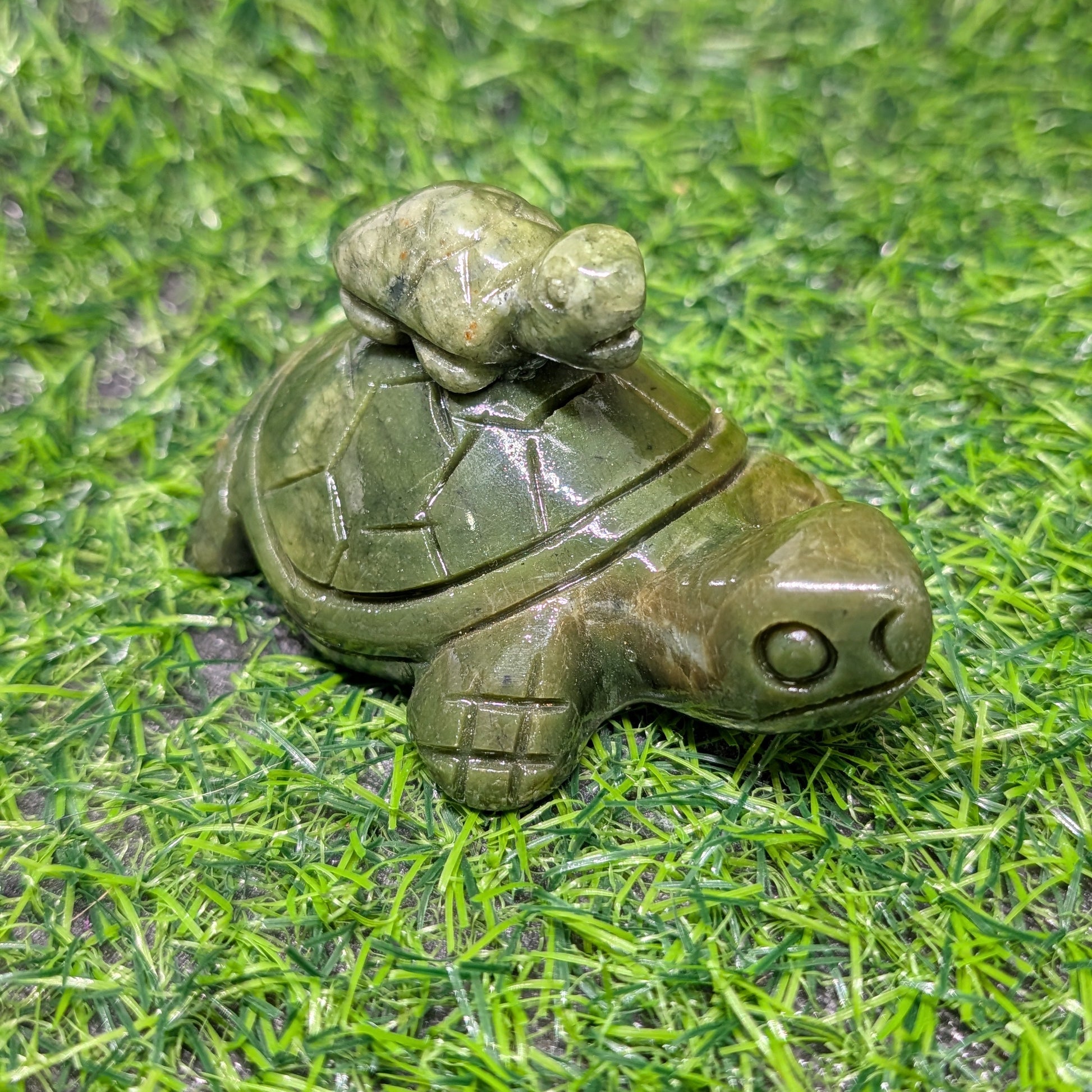 Decorative turtle figurine with a frog on its back on a grassy surface