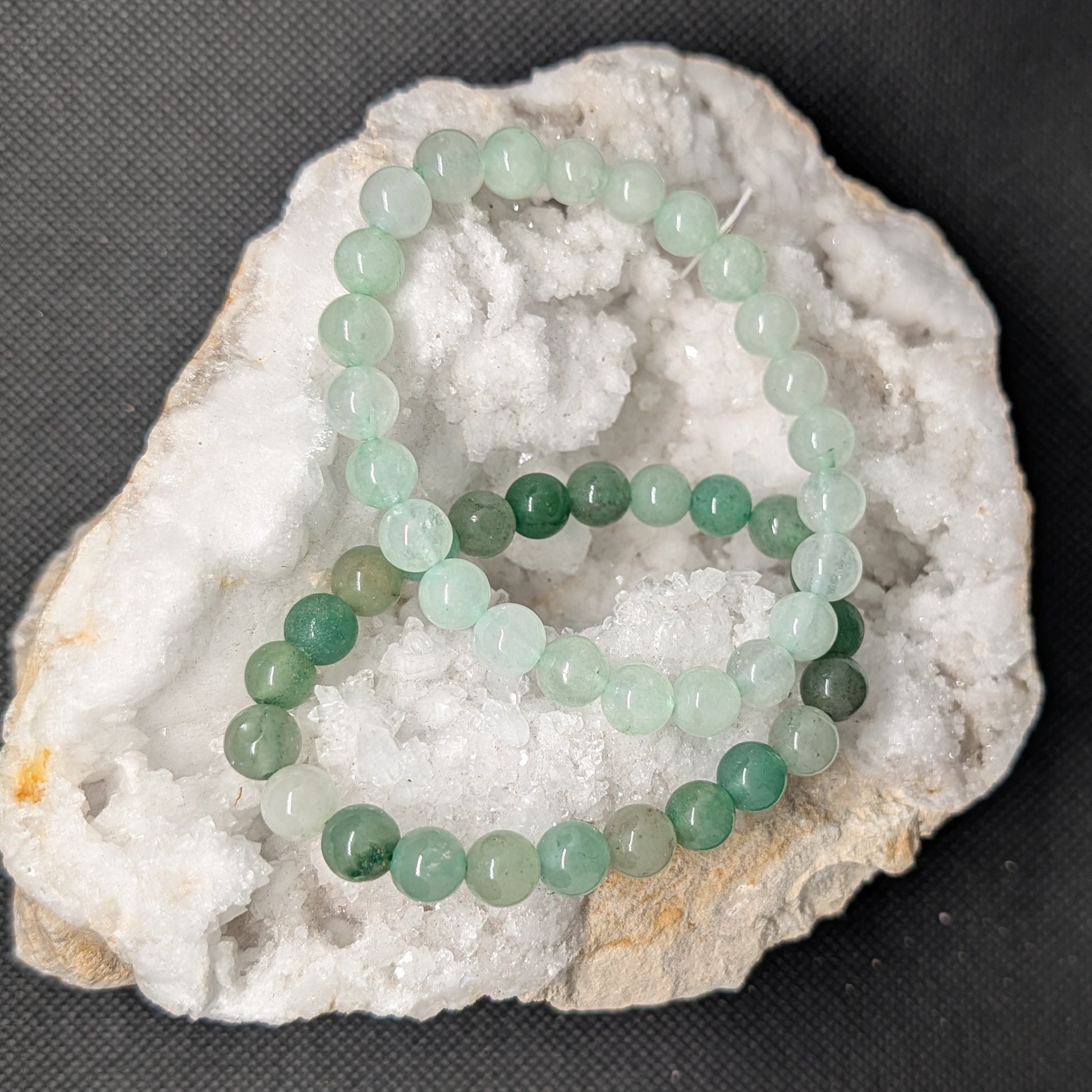 Green beaded bracelet on a white stone with a dark background