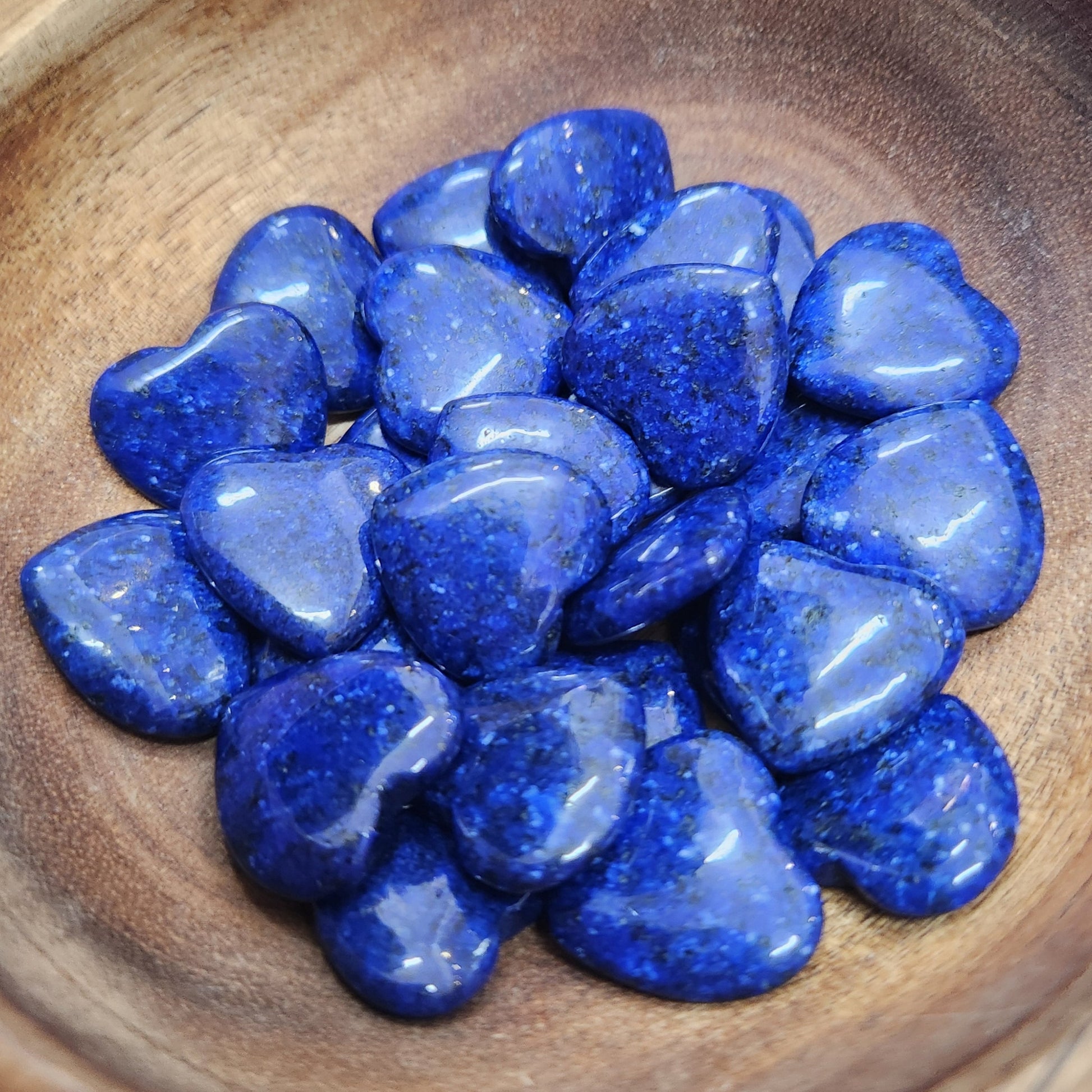 Blue stones in a wooden bowl on a white background