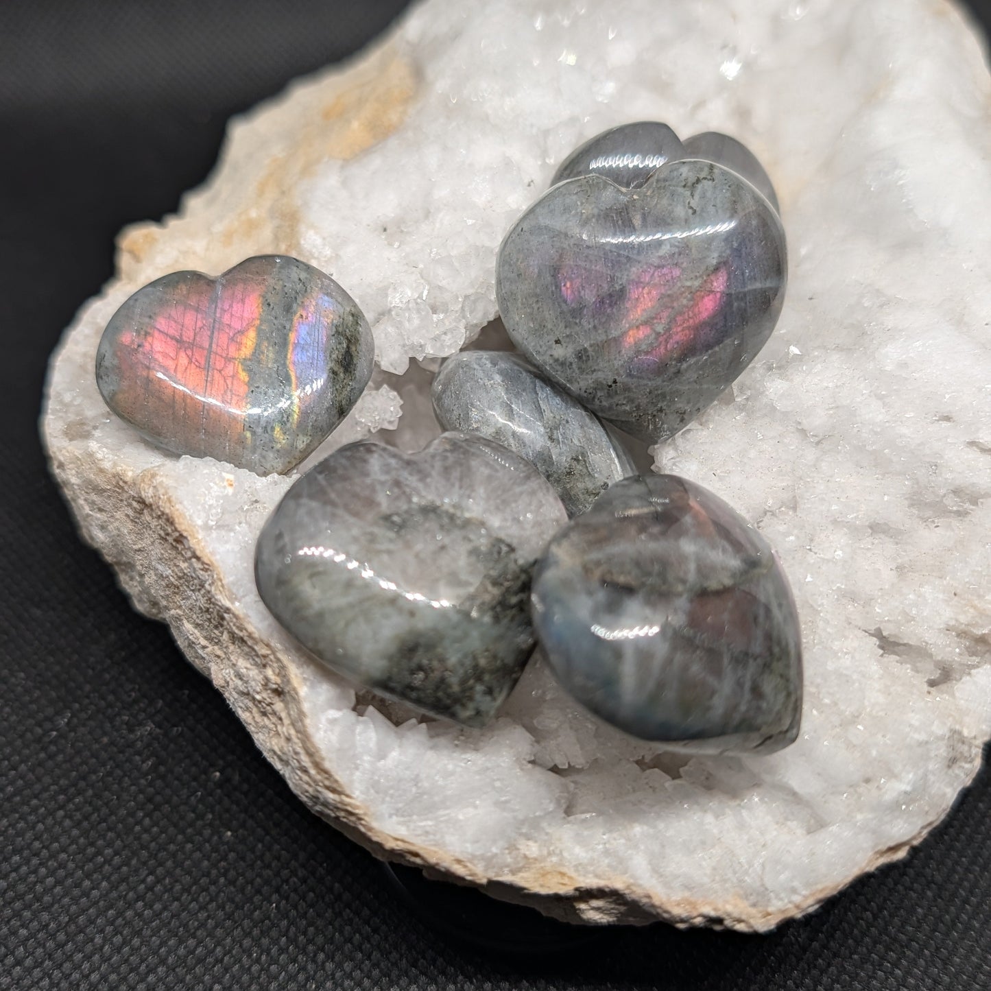 Heart-shaped opal stones on a crystal base with a dark background
