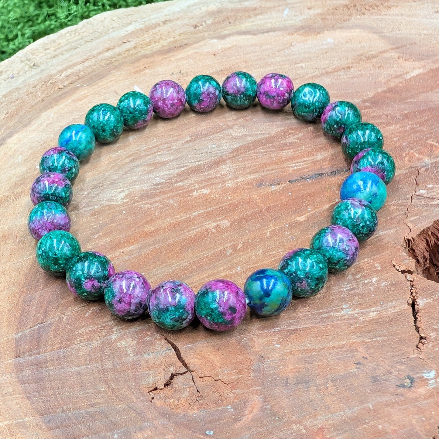 Beaded bracelet with green and purple beads on a wooden surface