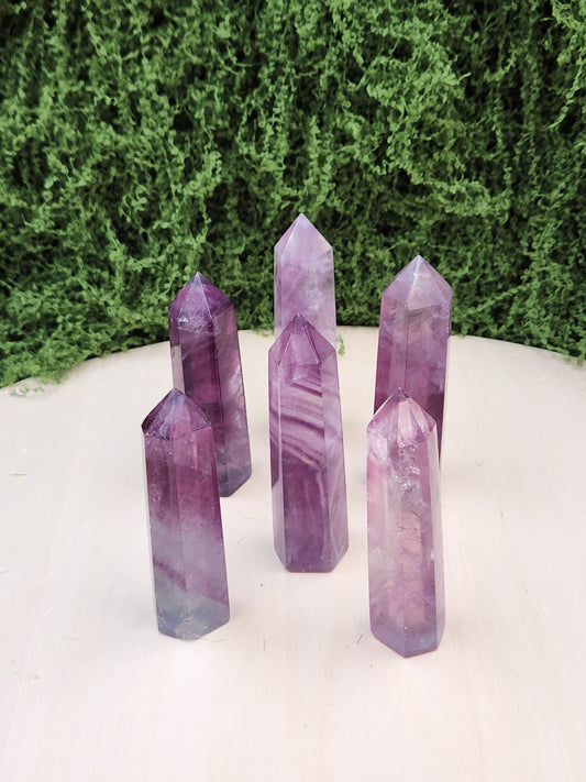 Purple crystal points on a white surface with greenery in the background