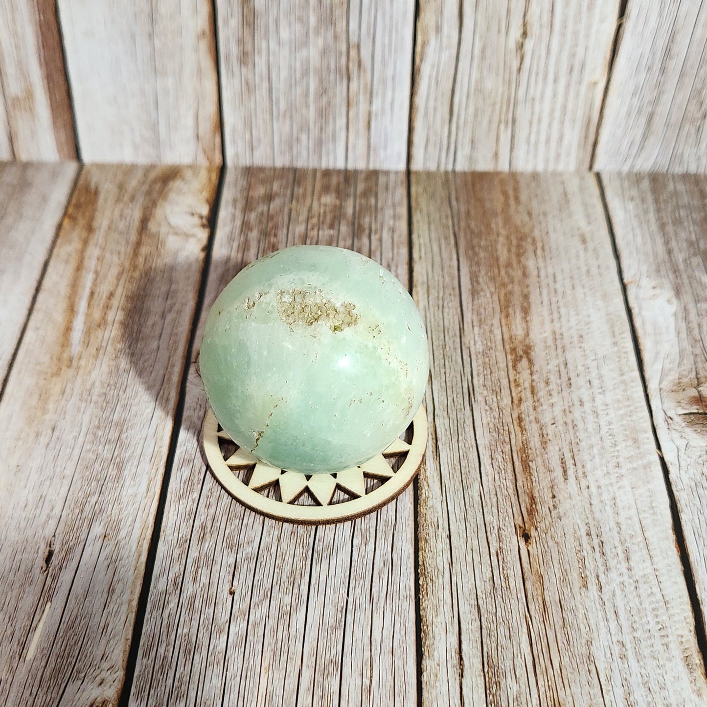 Decorative light fixture with a green glass shade on a wooden wall.
