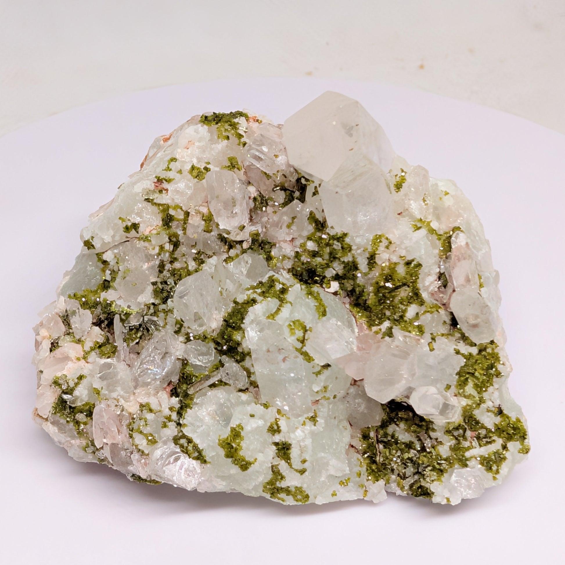 Mineral sample with green and white crystals on a white background