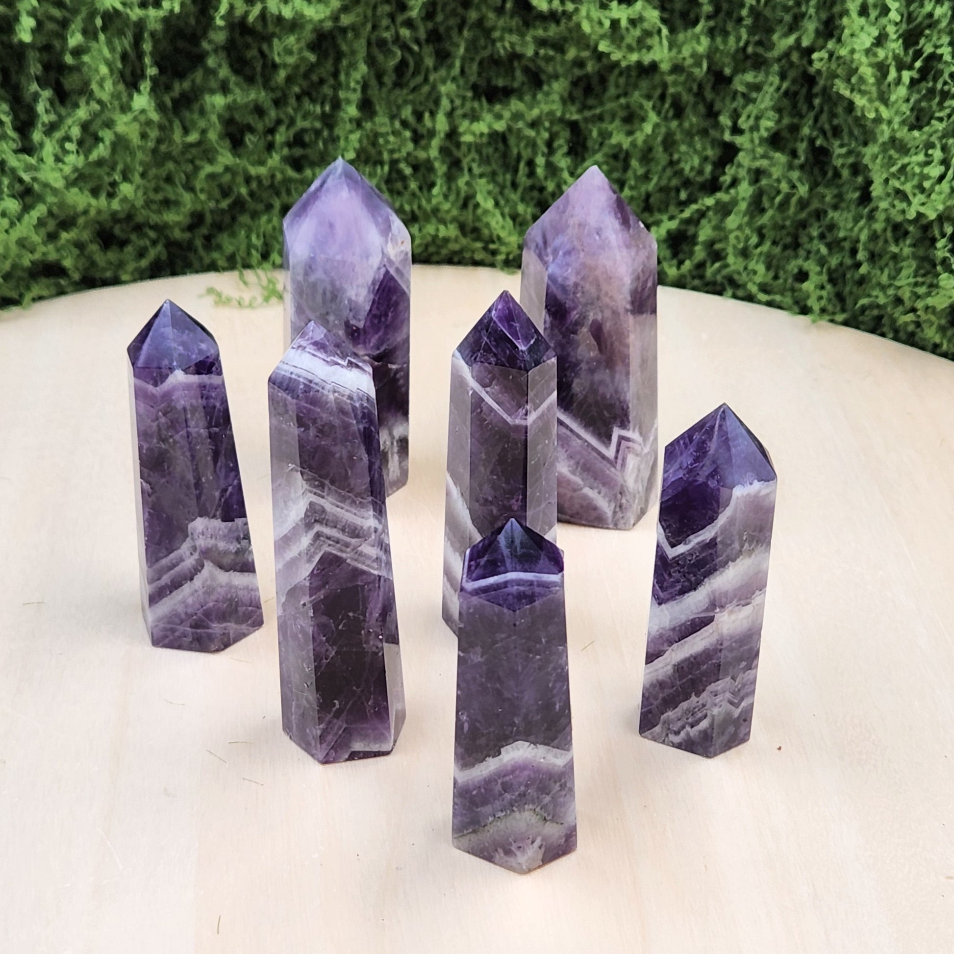 Set of purple crystal points on a white surface with greenery in the background
