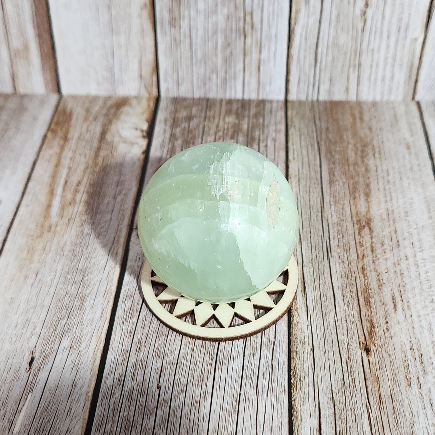 Decorative wall light fixture with a green glass shade on a wooden wall.