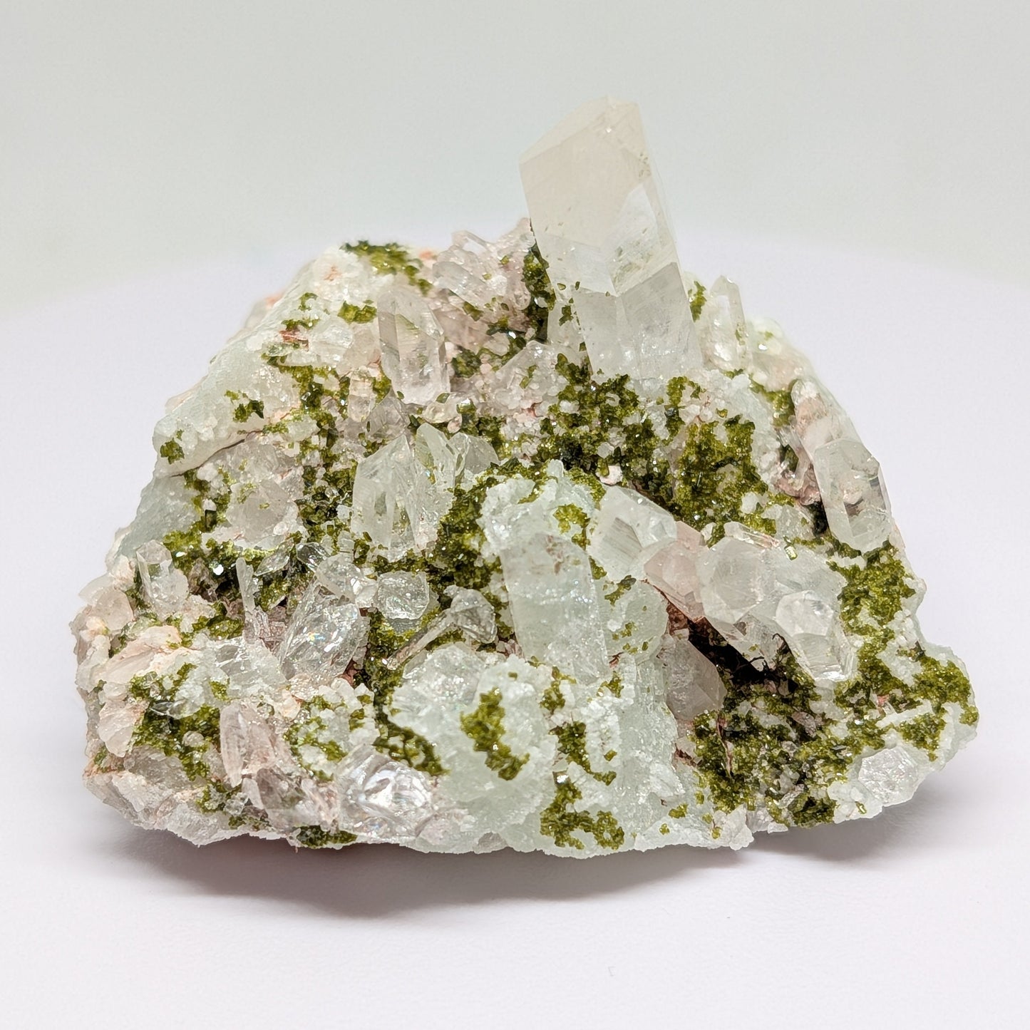 Mineral sample with green and white crystals on a white background