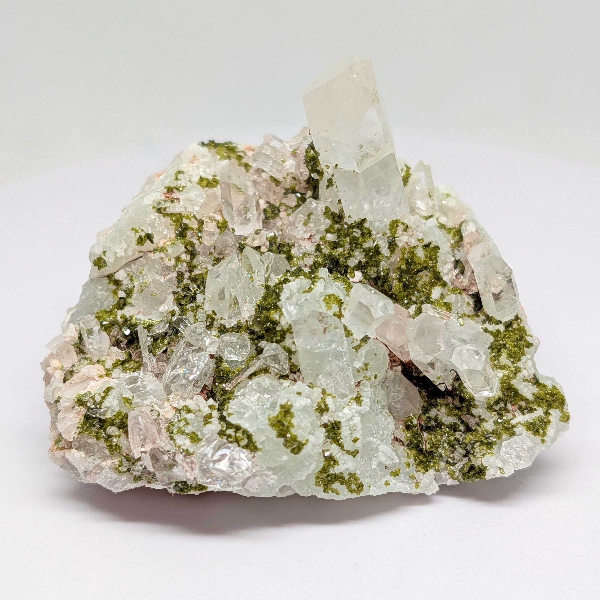 Mineral sample with green and white crystals on a white background