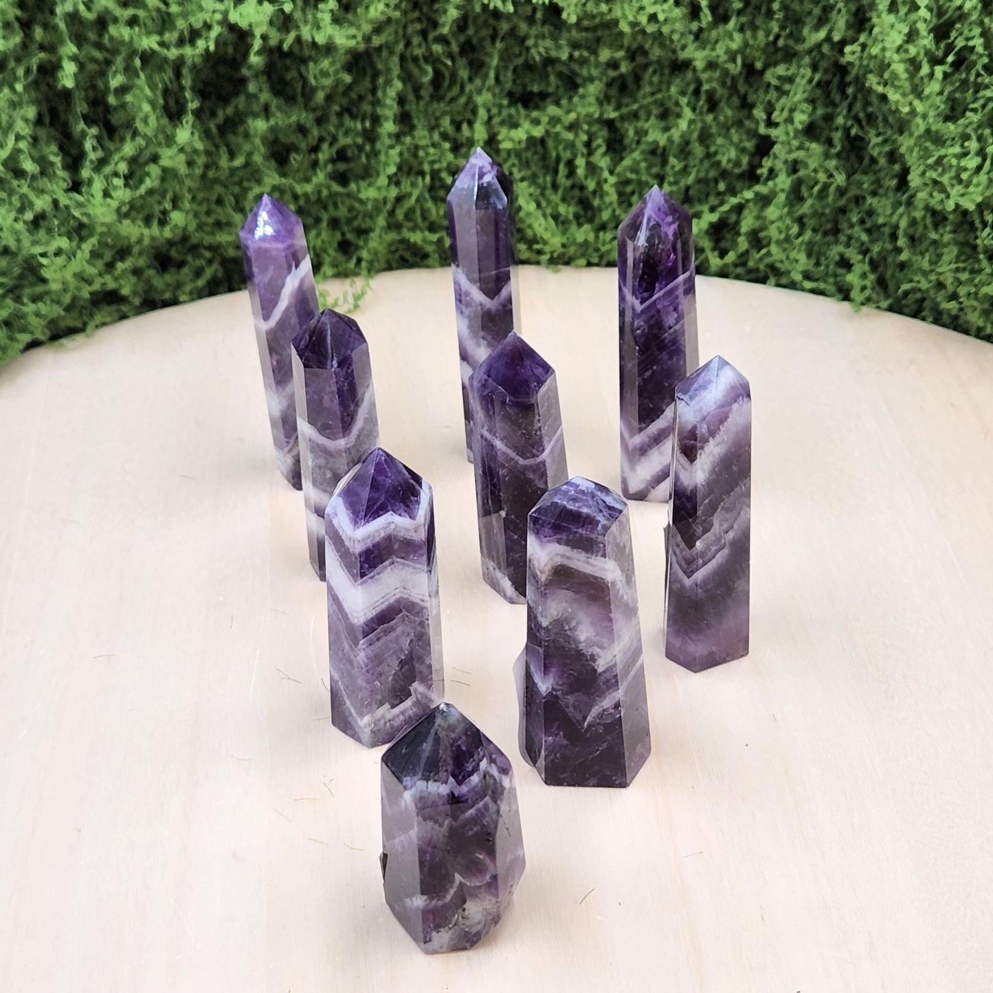Set of purple crystal points on a white surface with greenery in the background