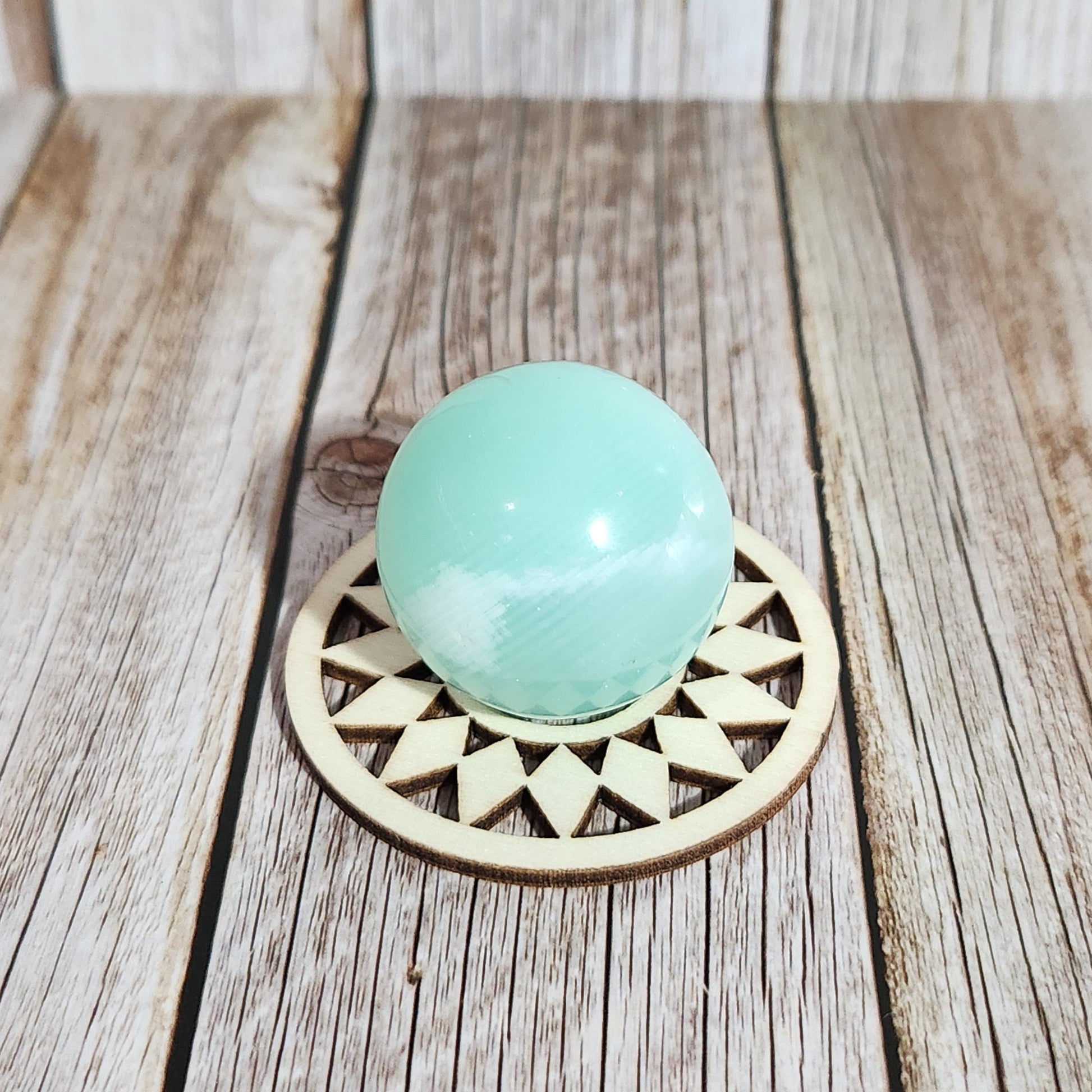 Decorative door handle with a turquoise ball and geometric design on a wooden surface