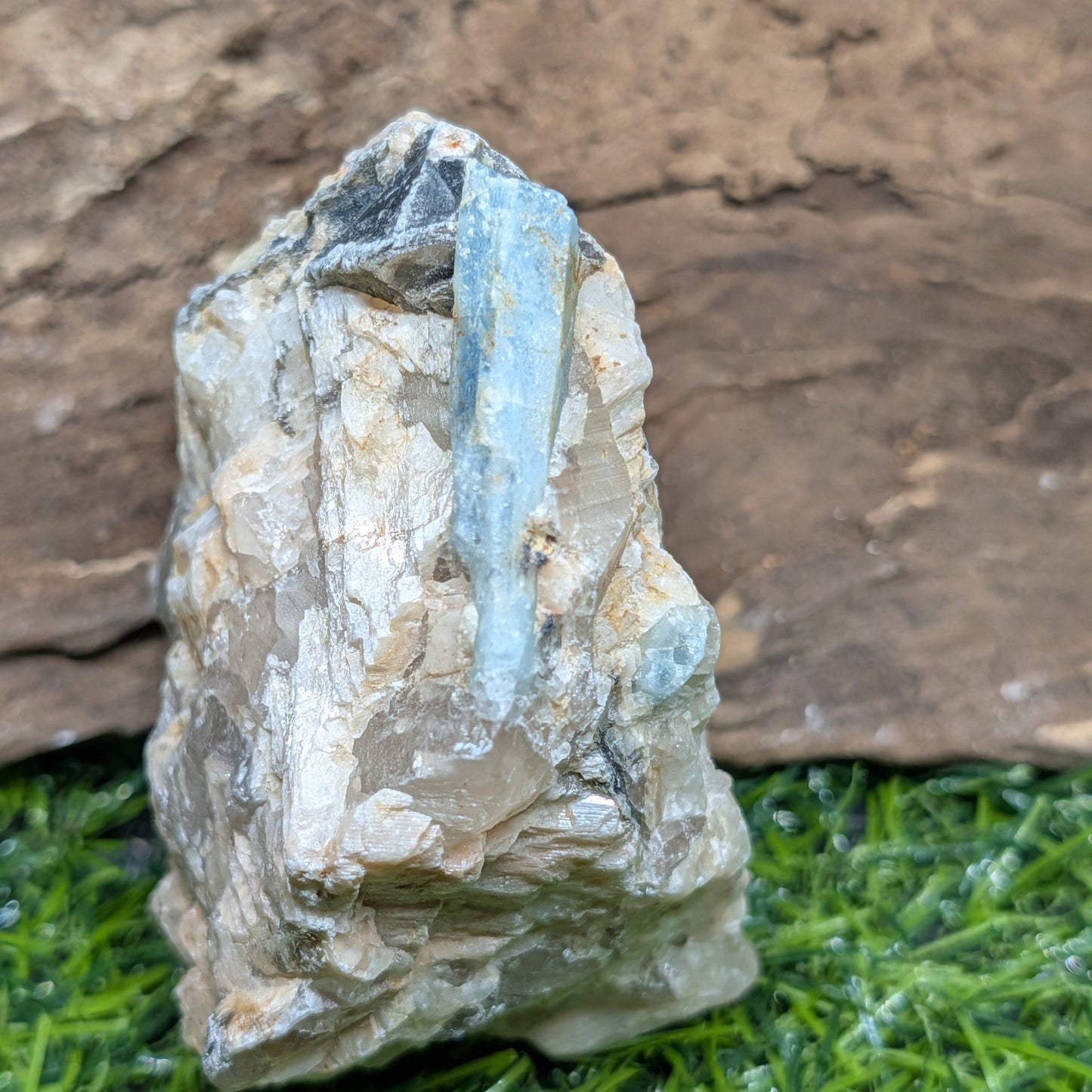 Mineral specimen on a grassy surface with a wooden background