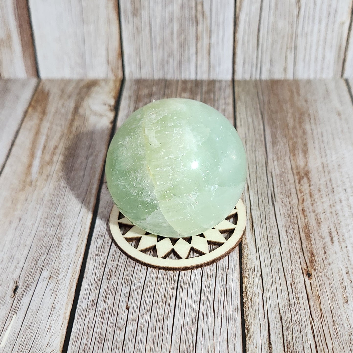 Green sphere with decorative cutout on a wooden surface