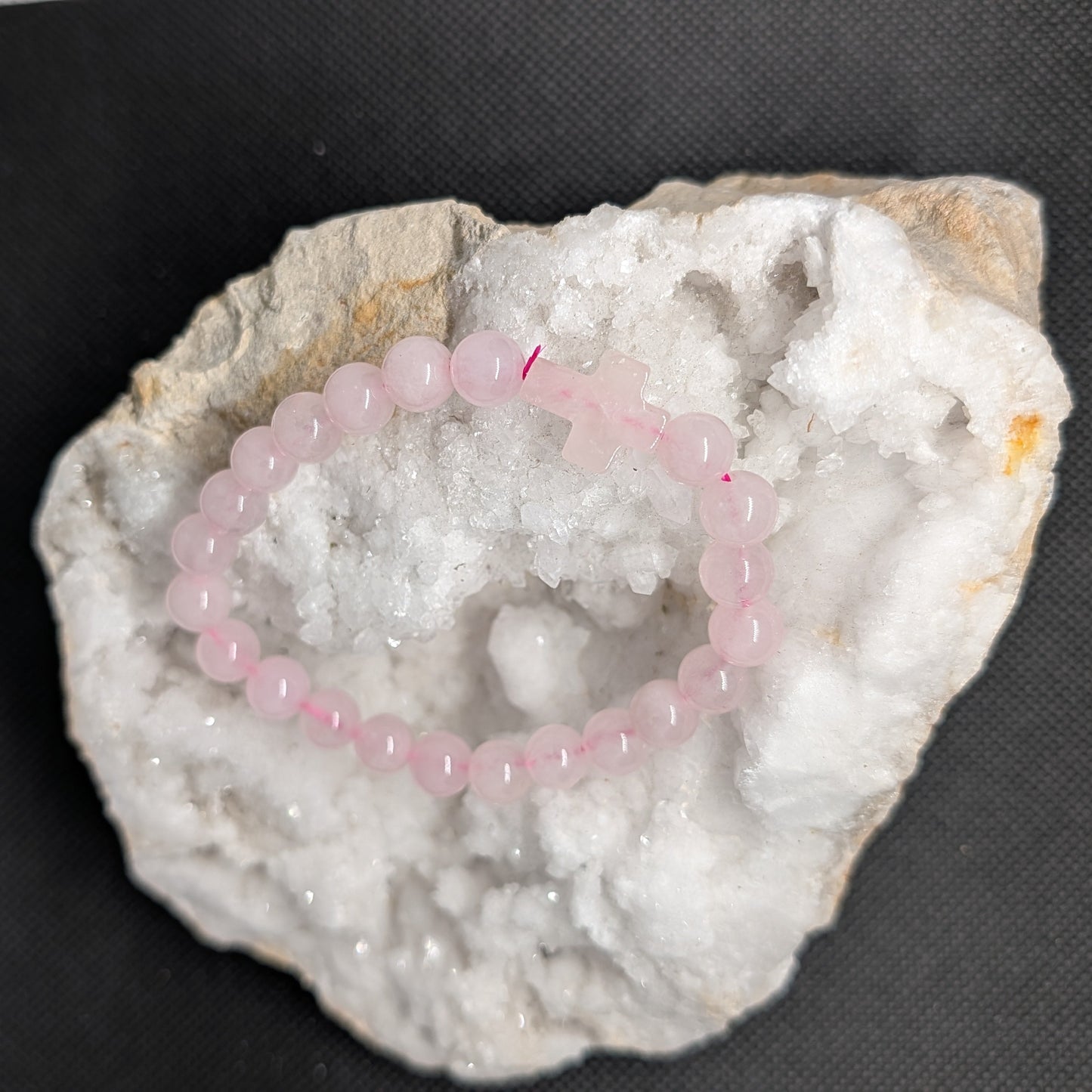 Pink beaded bracelet on a white crystal rock against a black background